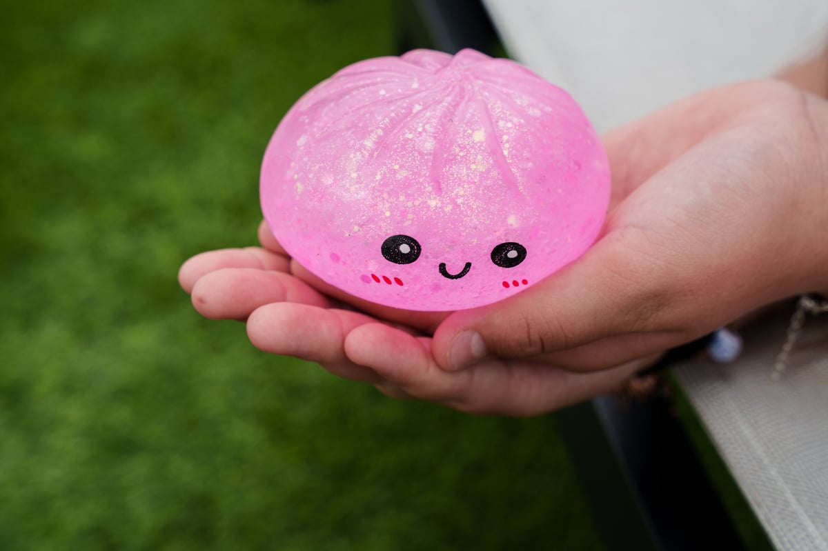 A child holding a pink glitter dumpling squishy, a trending anti-stress fidget toy for kids